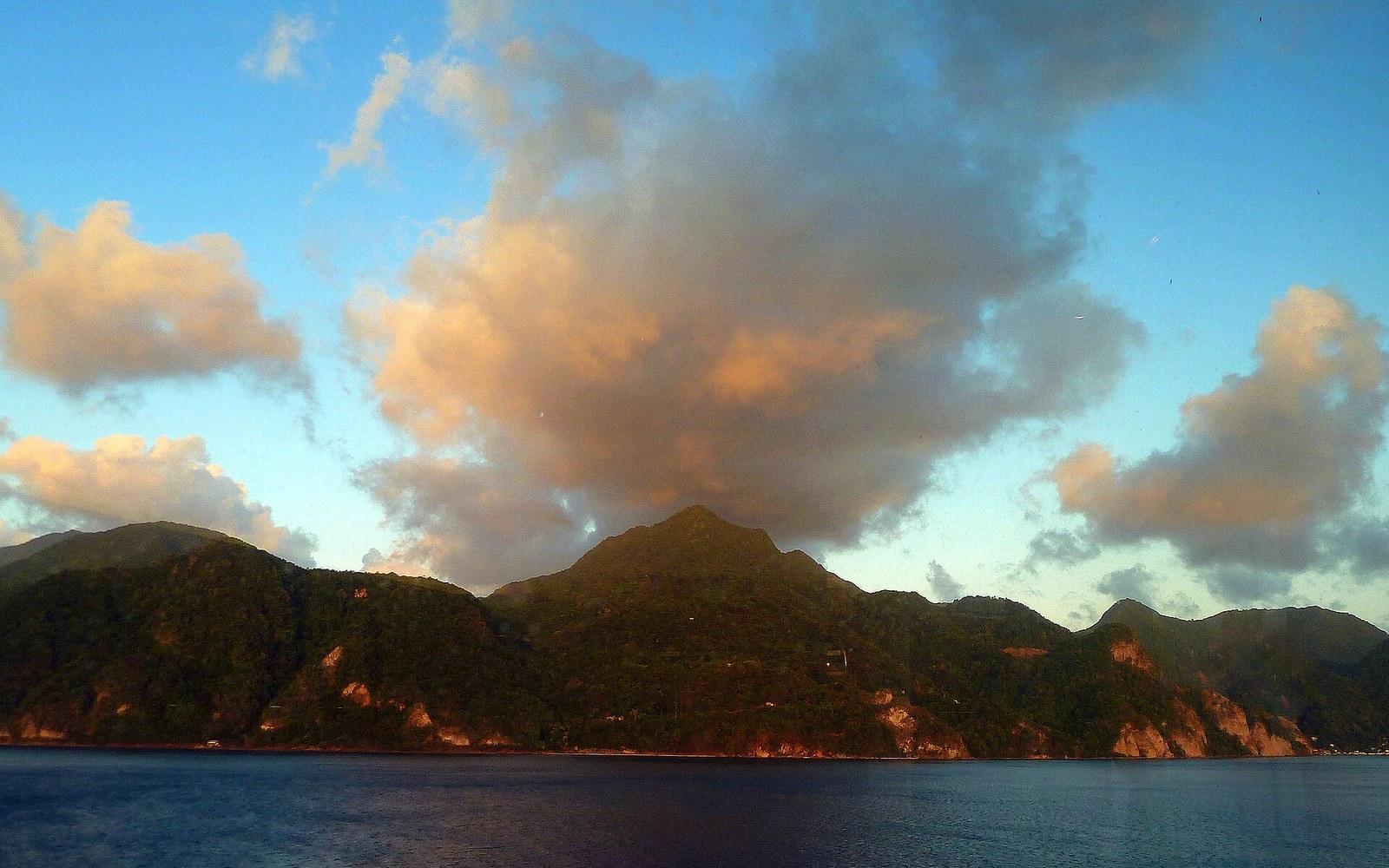 A steep volcanic coast under building cloud, wide